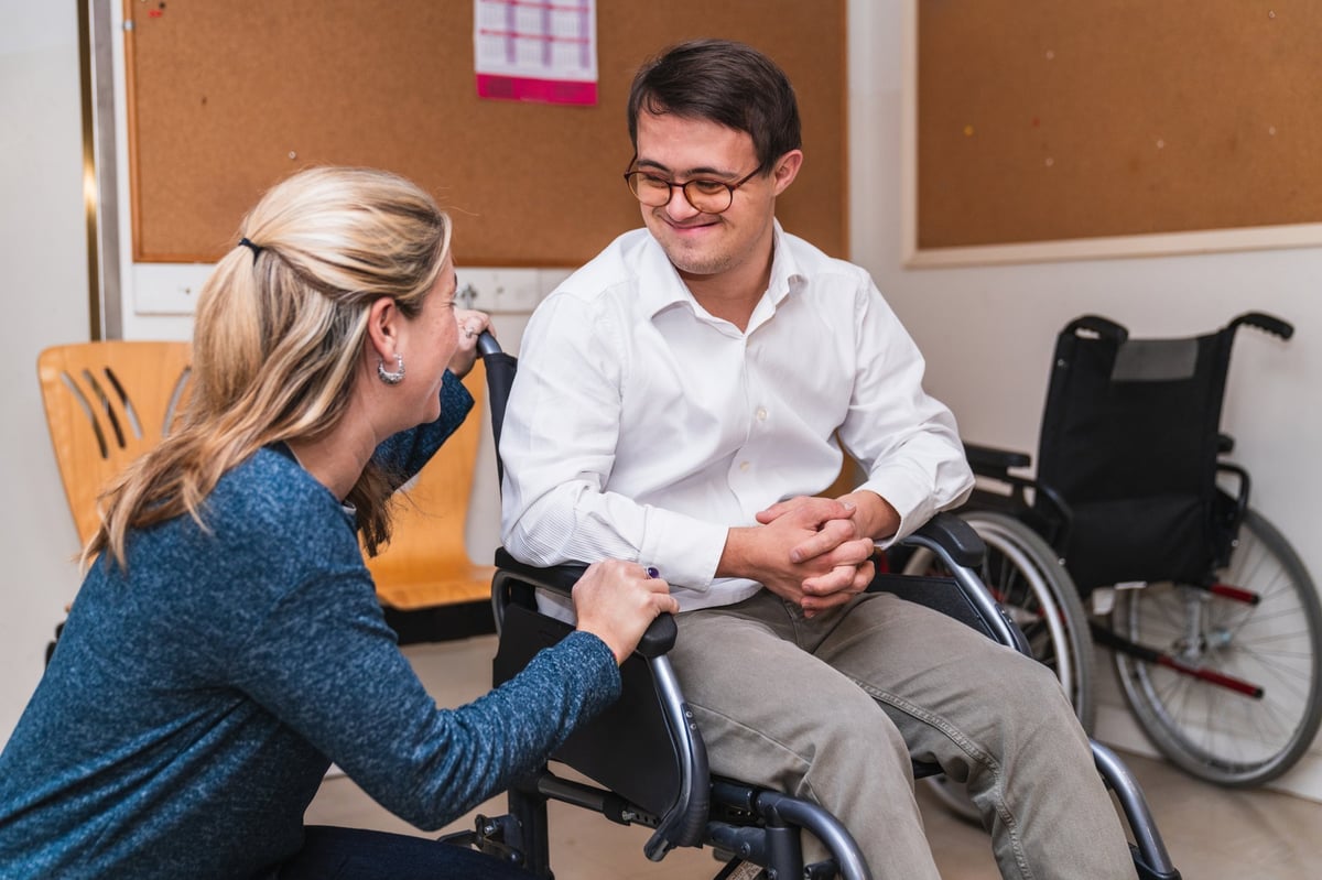 A heartfelt chat between a woman and a smiling man with Down Syndrome in a wheelchair