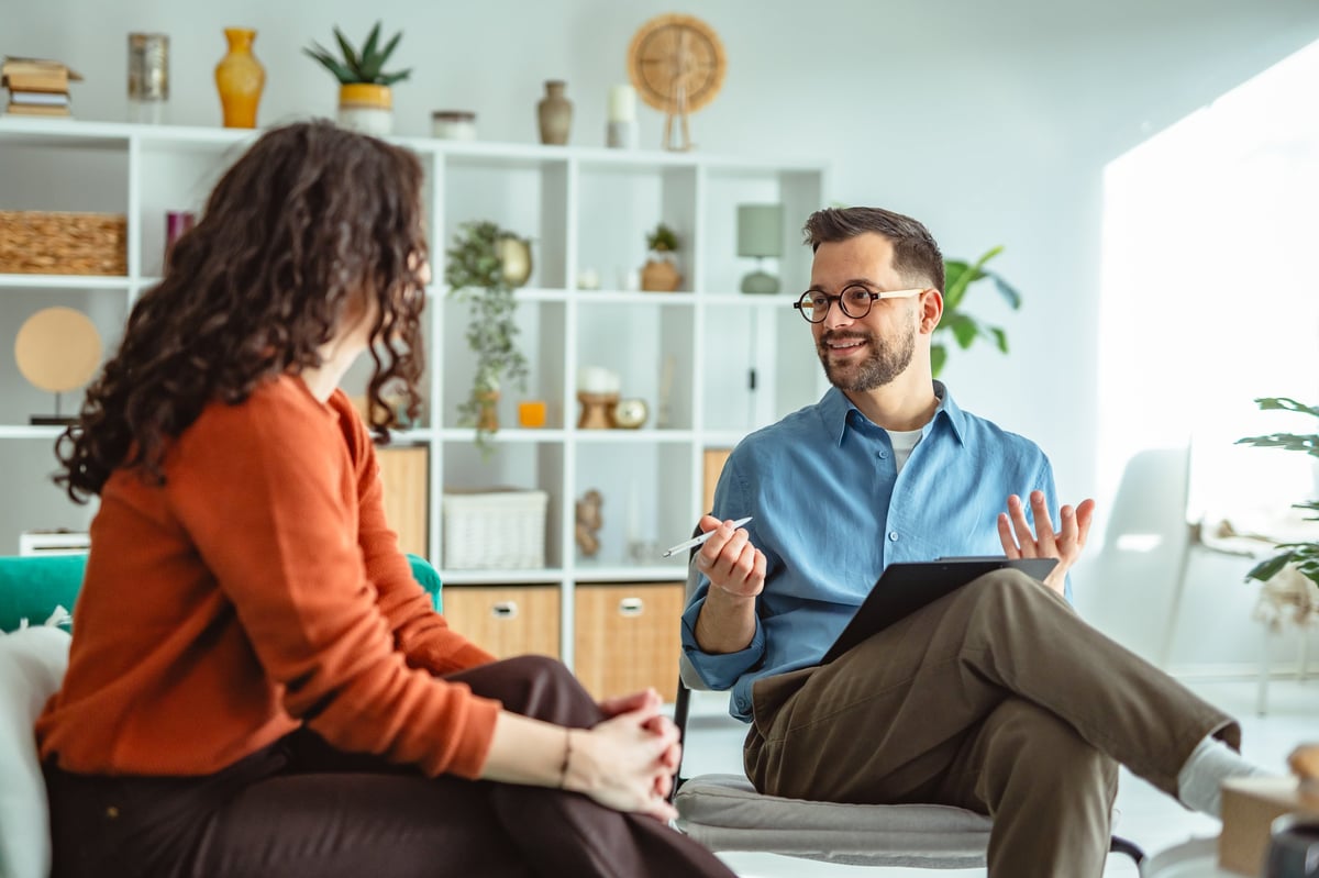 Young woman receiving support and advice from her male psychologist during a professional therapy session, both faces visible