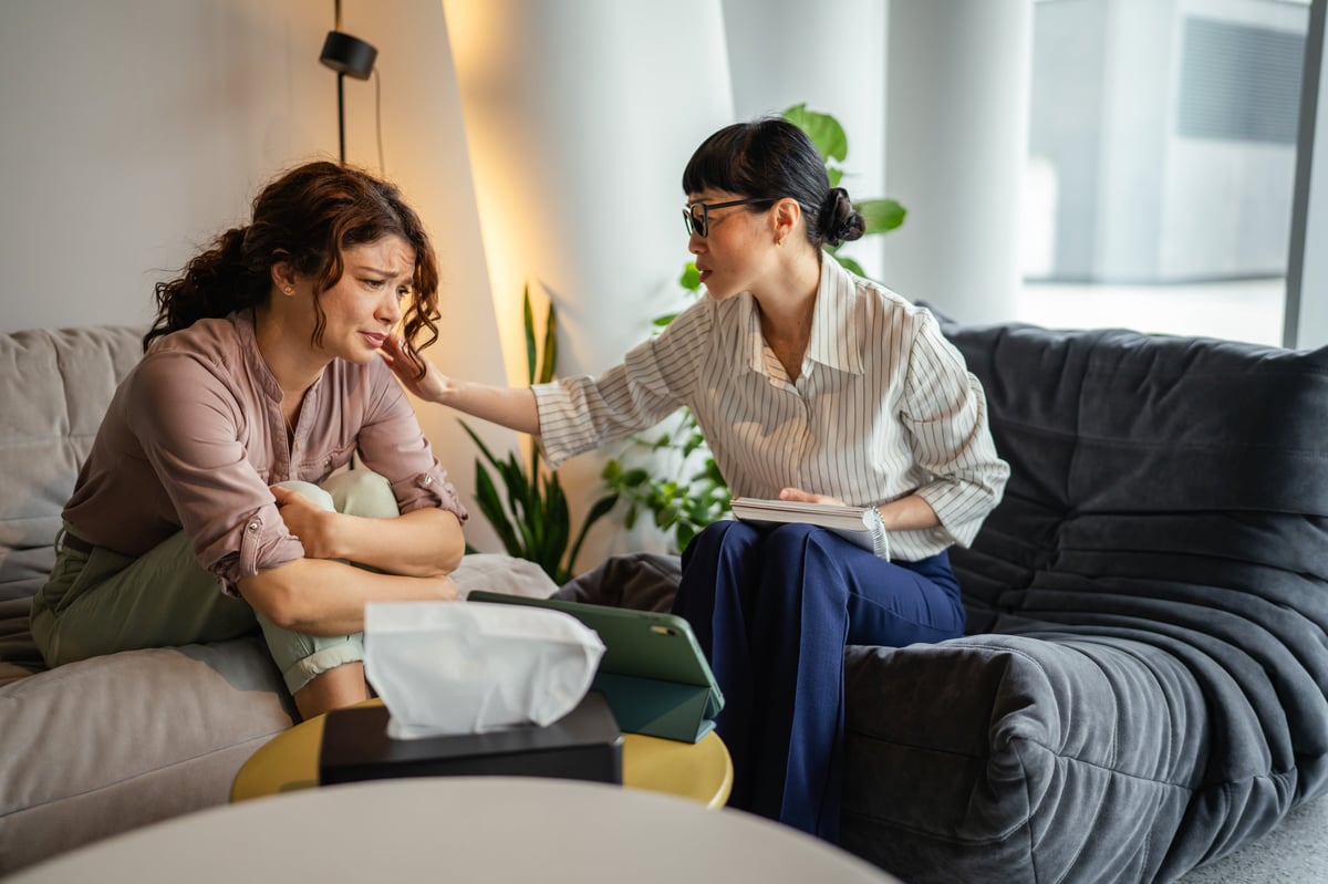 Two women having a supportive mental health conversation, therapist listening with empathy while the client shares her feelings during a coaching session